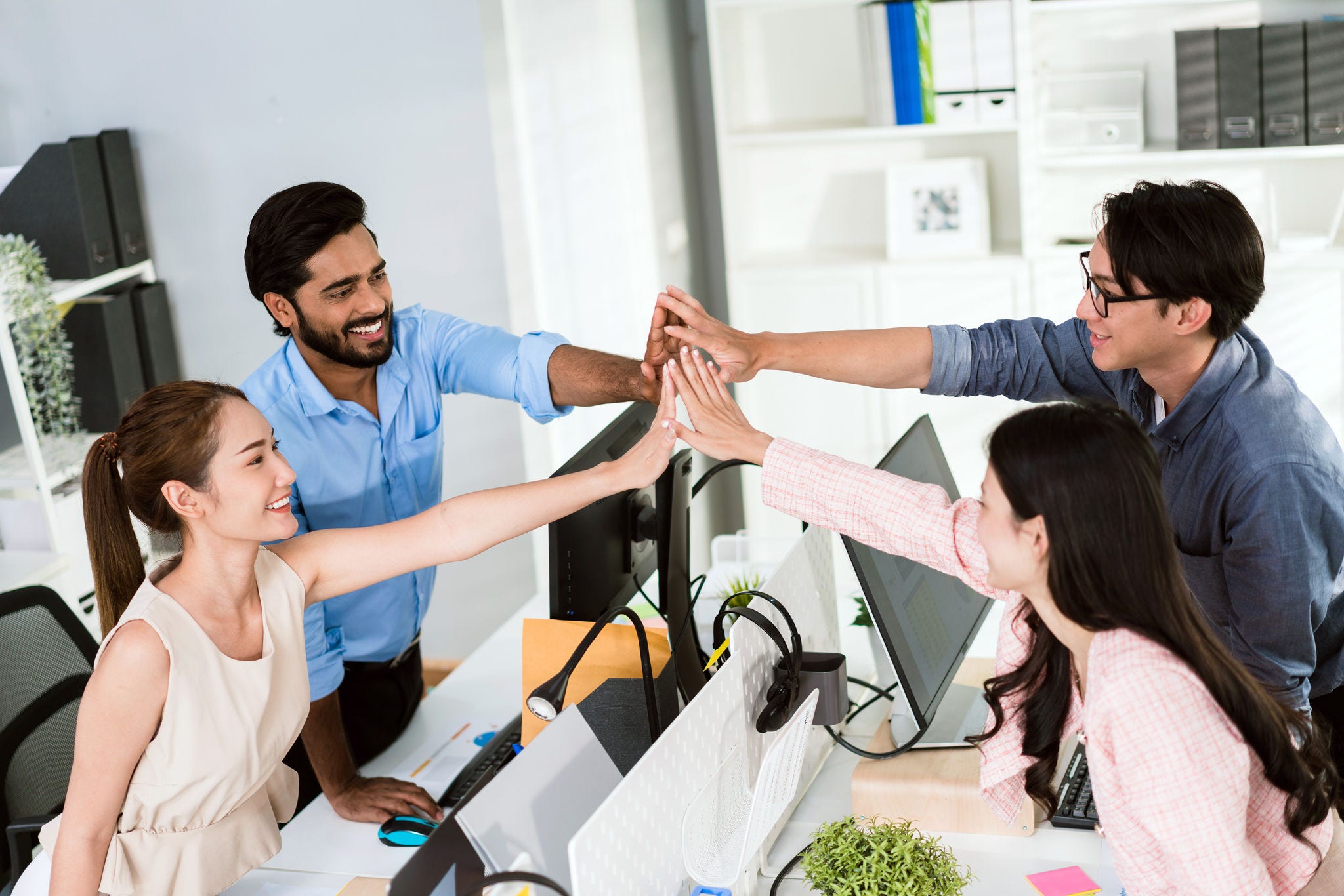 Team of young Asian, Indian and Thai entrepreneurs and startup have business meeting, encouraging and high five each other for good energy to accomplish successful marketing plan. Diversity of team.