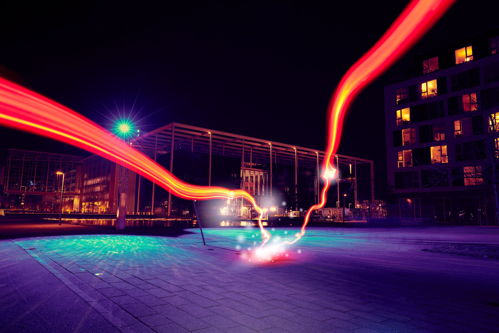 Red light runs through the residential area and hits the center in an explosion of light and energy. It is night, and the light trails light up in the dark. night photography, city lights, night,