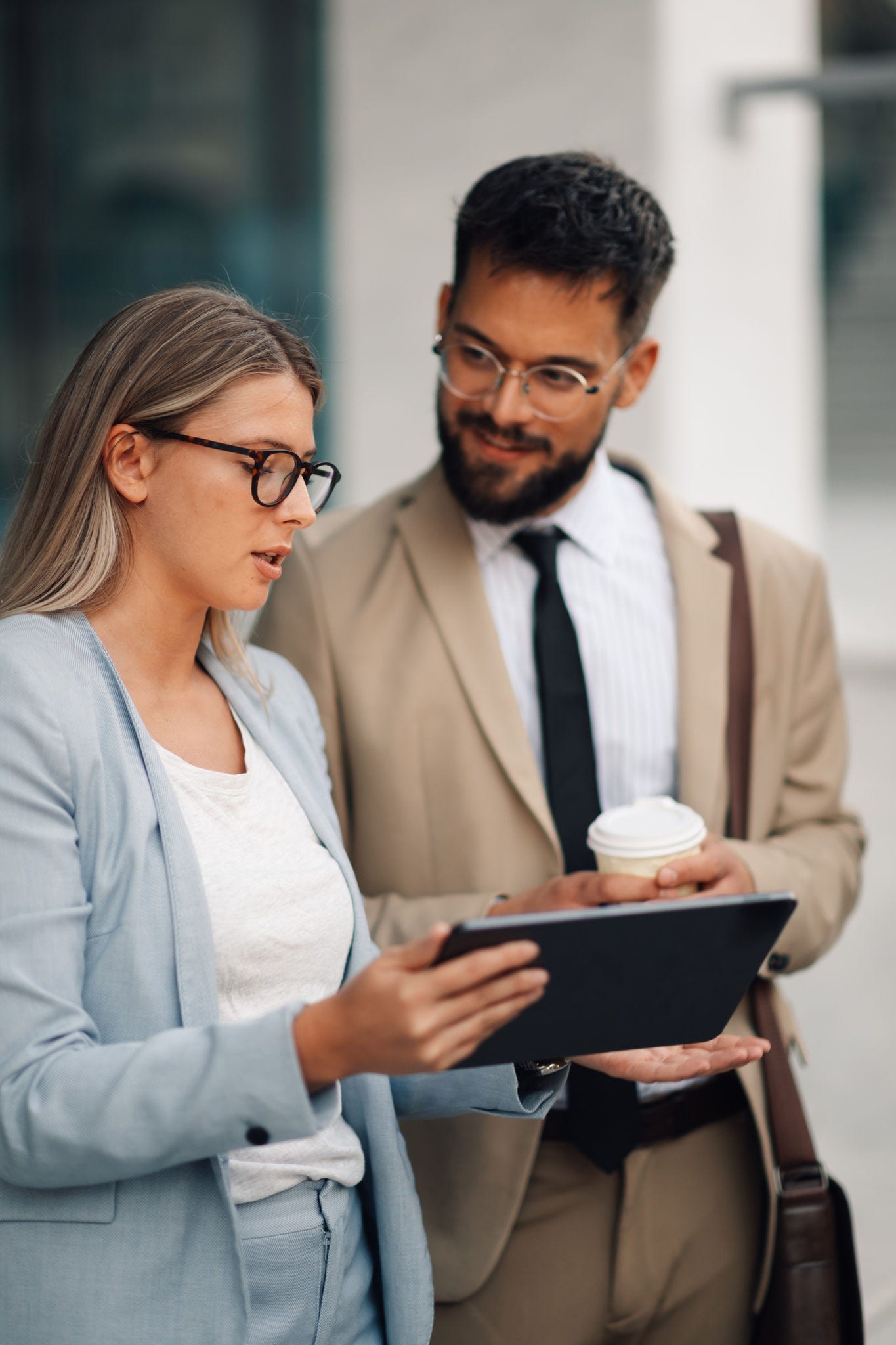 Businesswoman holding digital tablet having informal meeting with her male colleague outdoors. They are discussing new business opportunities