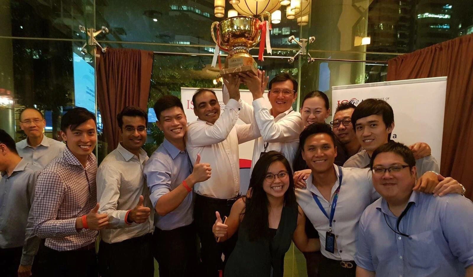 Retired Partner Leong Kok Keong celebrating ISCA Games win with colleagues with the iconic trophy