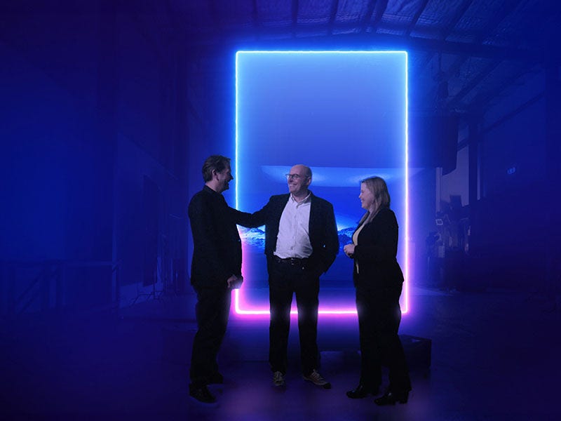 KPMG colleagues having discussion in front of glowing blue-pink frame