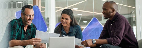 People in conversation sat at a table with documents and a laptop