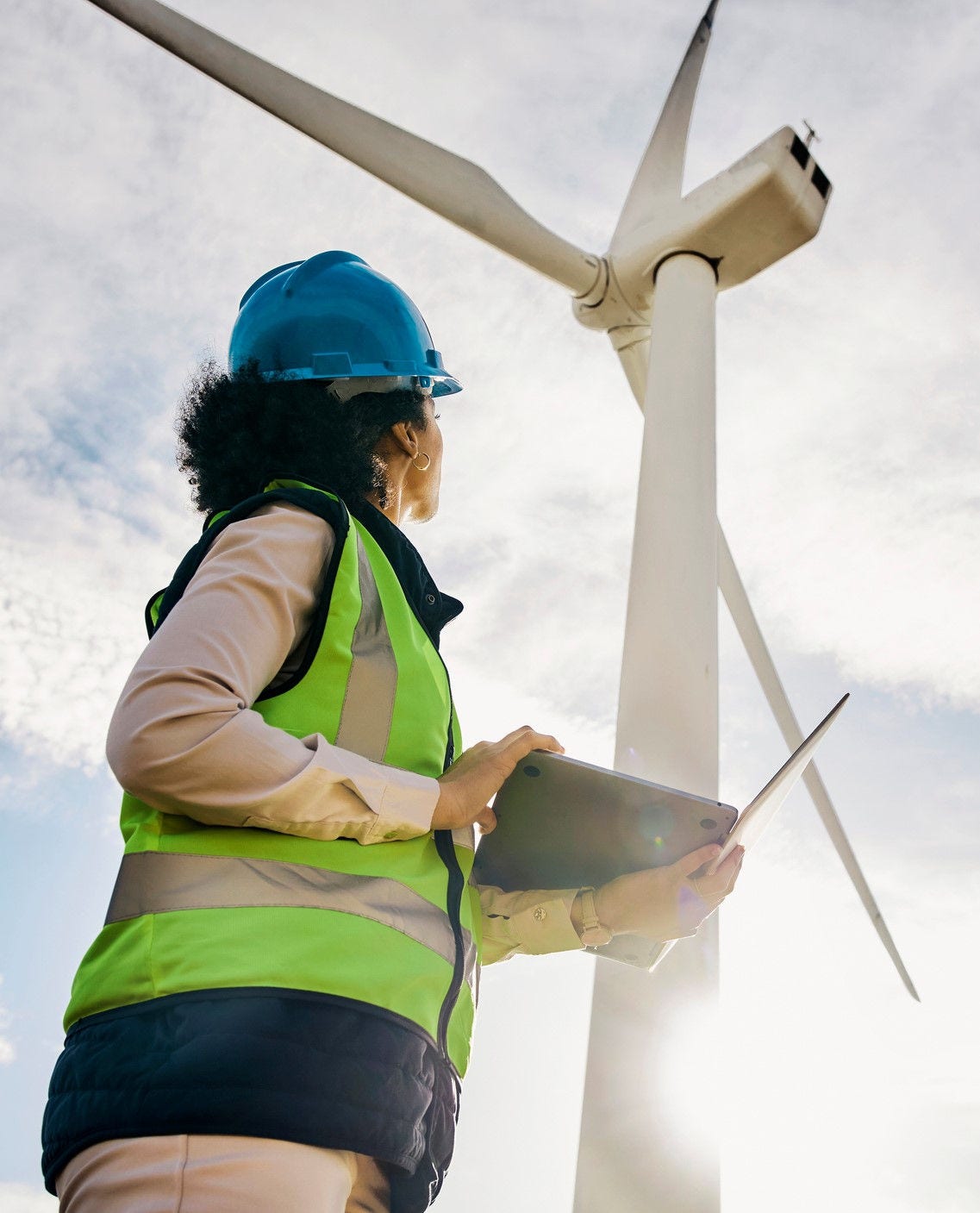 Engineer woman, wind turbine and laptop on farm for renewable energy, power and electricity. Electrician or technician in nature for windmill, eco and green environment inspection and maintenace