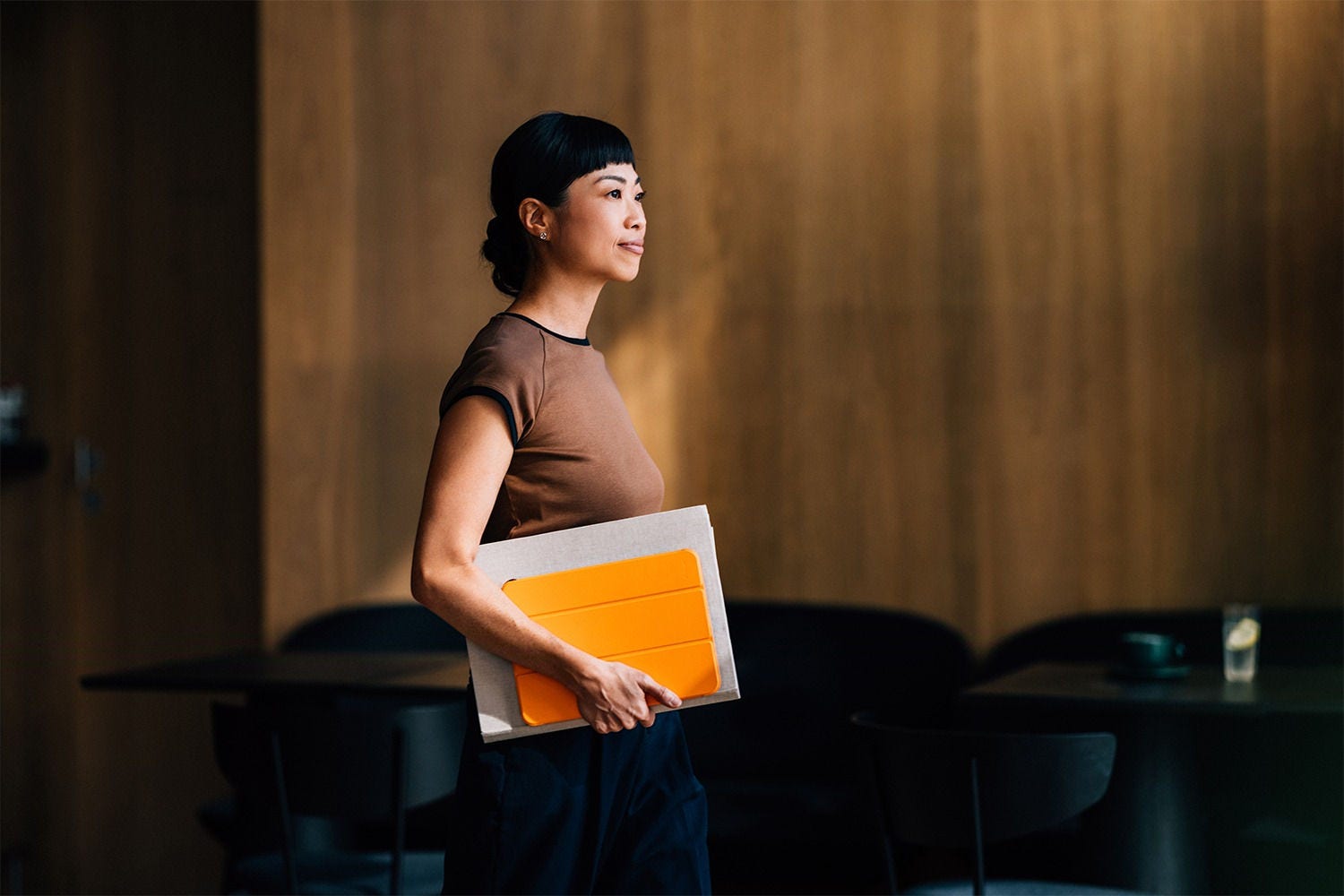 Person walking with documents and a tablet in an indoor space