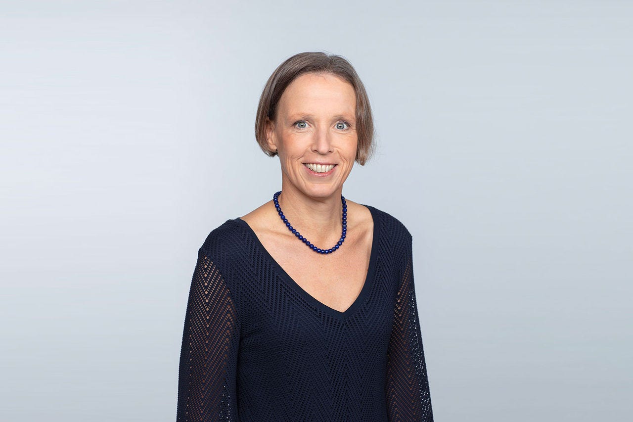 Porträt von Bettina Matzka vor einem hellgrauen Hintergrund