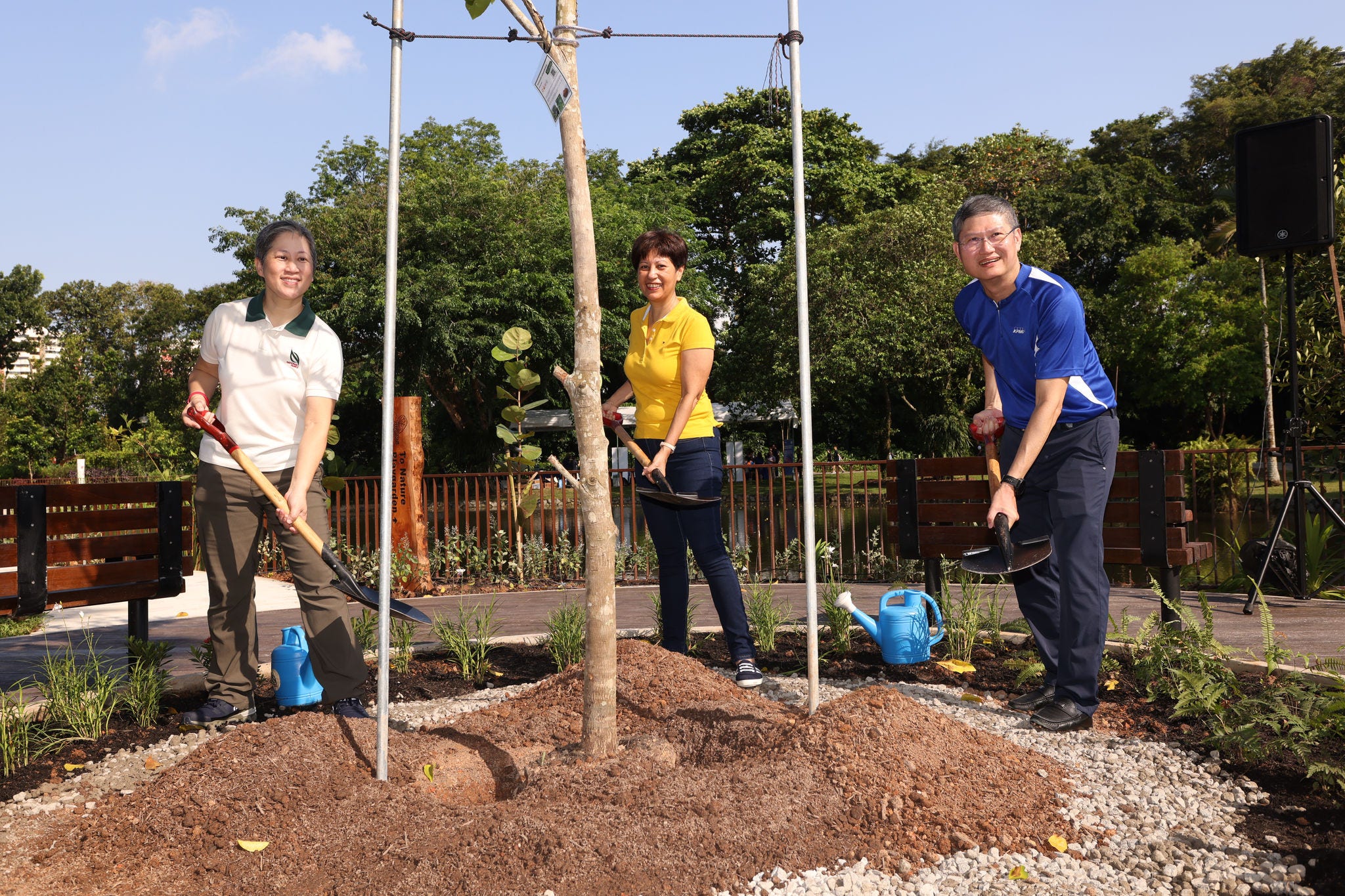 An NParks representative, Minister Indranee Rajah, and Managing Partner Ong Pang Thye plant a tree together at the KPMG Wellness Garden