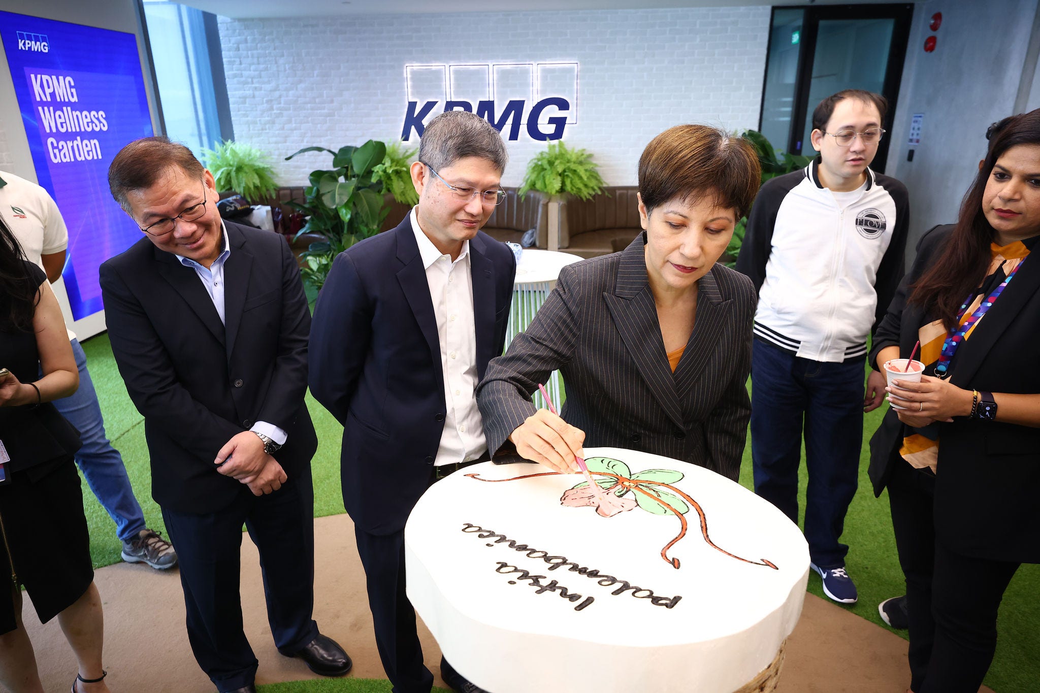 Guest of honour Minister Indranee Rajah paints a tree cookie at the KPMG Clubhouse, while Managing Partner Ong Pang Thye and Partner Tay Hong Beng looks on at the official opening of KPMG in Singapore's office at Asia Square