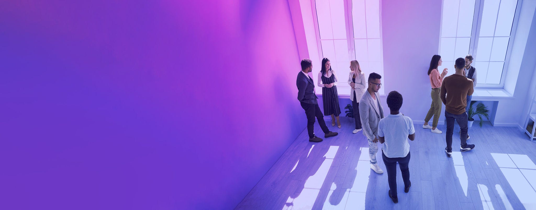 Diverse people talking in groups during a meeting. High angle shot of different young community members or company employees standing in a modern office room, discussing something, sharing opinions