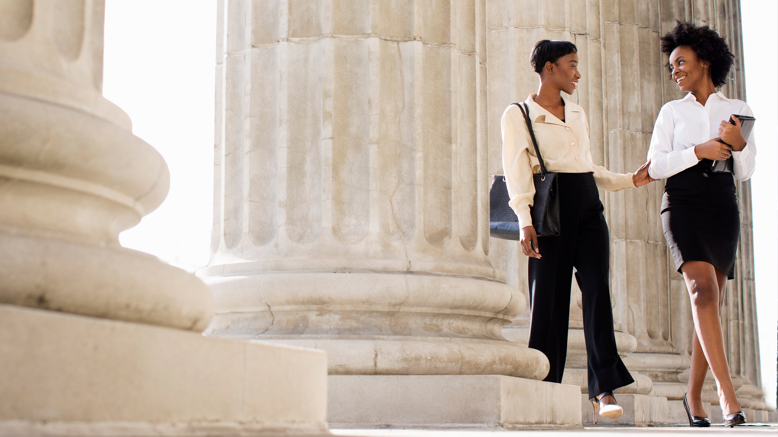 Two African American women standing near pillared building entrance
